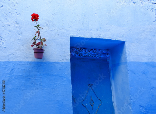 Door, blue wall and red flower vase in blue city Chefchaouen, Morocco © Gisela Fiuza