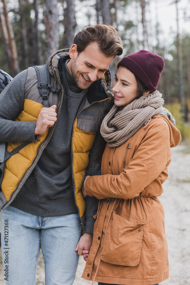 Fototapeta premium young woman hugging boyfriend while walking in autumn forest