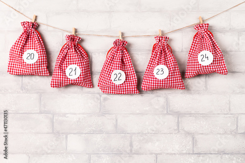 Christmas advent calendar. Gift bags hanging on white brick wall. December concept