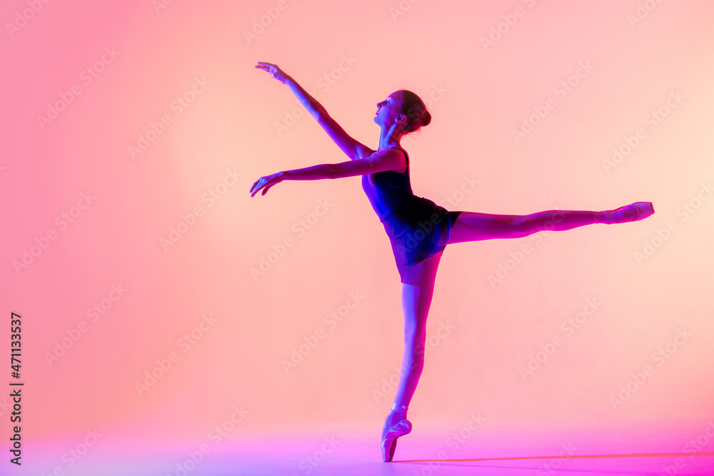 Beautiful young girl ballerina in pointe shoes and a swimsuit silhouette on a bright red background.