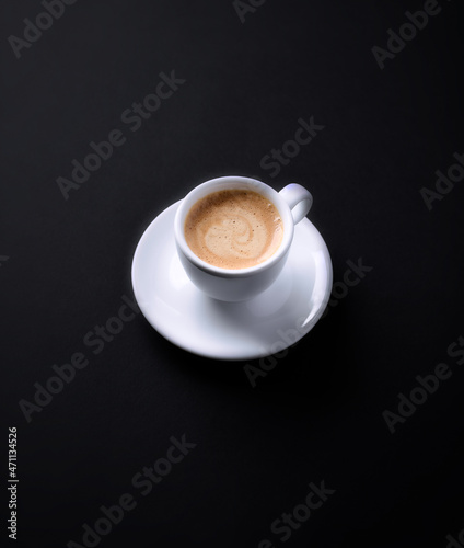 Cup of coffee on black paper background. Copy space.