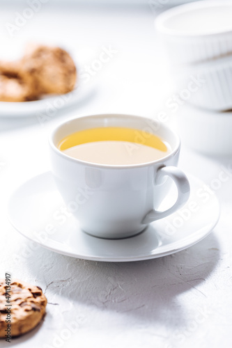 Cup of tea in white cup with chocolate chip cookies as a part of a scene, on a white background