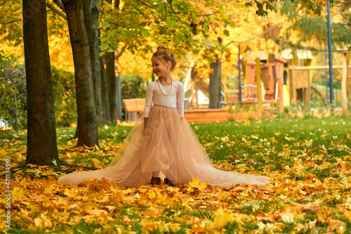 Little girl princess in yellow autumn in fluffy skirt. Orange greens and happy child playing outside. Fun outdoor play in the new park near your home. Childhood concept. Laughs and smiles beautifully.
