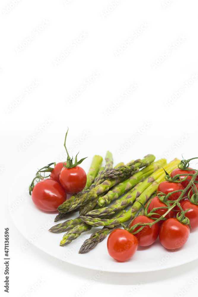 Spargel und Kirschtomaten auf weißem Hintergrund