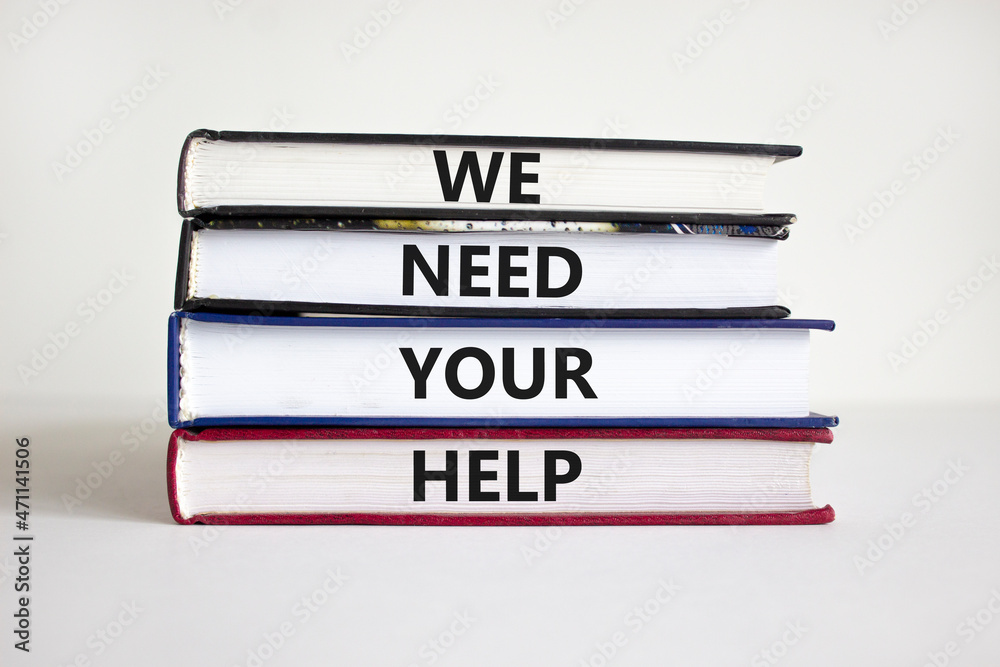 Obraz premium We need your help symbol. Books with concept words 'We need your help'. Businessman hand. Beautiful white background. Business, support and we need your help concept. Copy space.