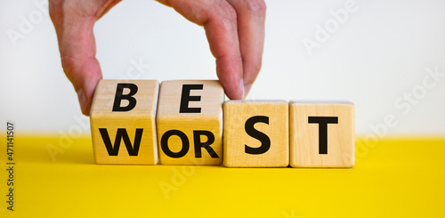 Best or worst symbol. Businessman turns wooden cubes and changes the word best to worst. Beautiful yellow table, white background, copy space. Business and best or worst concept.