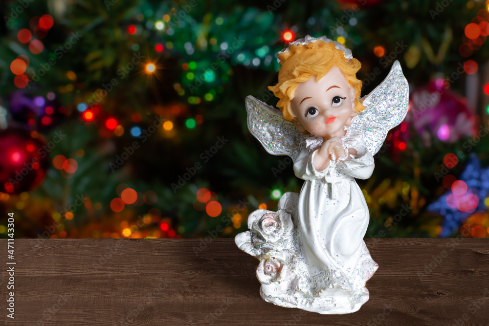 figurine of an angel in white on the background of a christmas tree copy space