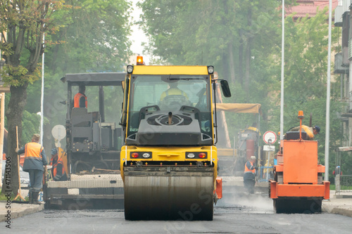 Laying of new modern asphalt. Asphalt laying equipment works on the site. A yellow asphalt skating rink rides in close-up on a new roadbed.