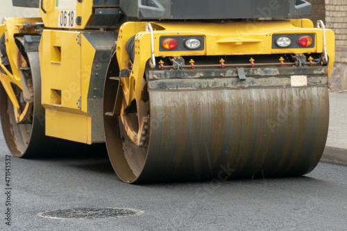 Laying of new asphalt on a city street. Large equipment for laying and tamping asphalt is working on the road. The use of a roller when laying asphalt ensures absolute evenness of the coating.