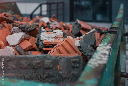 Canvastavla Green metal skip full of broken brick and stone material on construction site