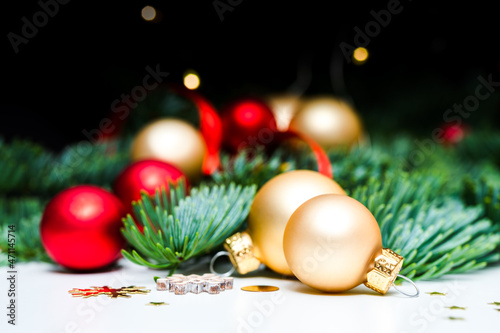Decorating for Christmas holiday. Golden and red shimmering Christmas baubles, fir green, confetti stars and Christmas lights on white background.