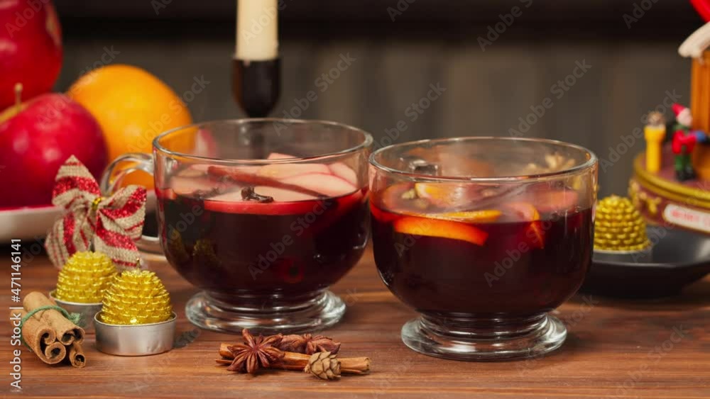 Mulled wine in glasses, gluhwein close-up. Hot red wine with apples, oranges, cinnamon, star anise. Winter traditional drinks. Christmas holidays and new year time, blowing out candles. Mulled wine in glasses, gluhwein close-up. Hot red wine with apples, oranges, cinnamon, star anise. Winter traditional drinks. Christmas holidays and new year time, blowing out candles.