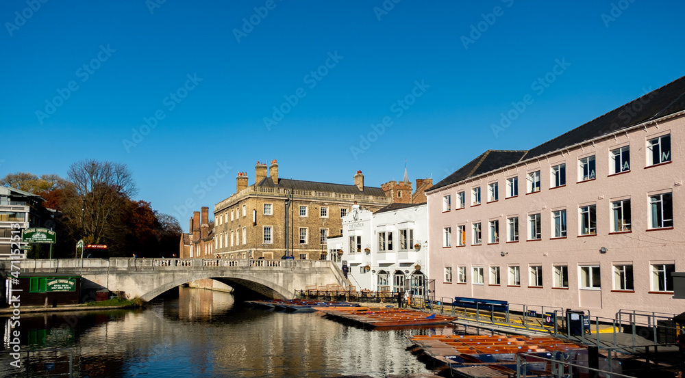 Cambridge, Cambridgeshire, UK – November 2021. Traditional wooden punts moored in Scudamore’s yard on the River Cam in the city of Cambridge. Nearby is The Anchor Pub and Silver Street Bridge