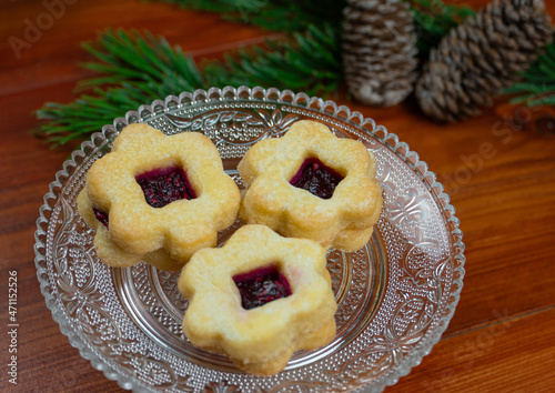 Delicious Christmas cookies on a glass dish. Fir branches and pine cones in the background.