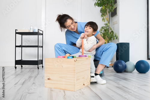 Therapist doing development activities with a little boy with cerebral palsy, having rehabilitation, learning . Training in medical care center. High quality photo.