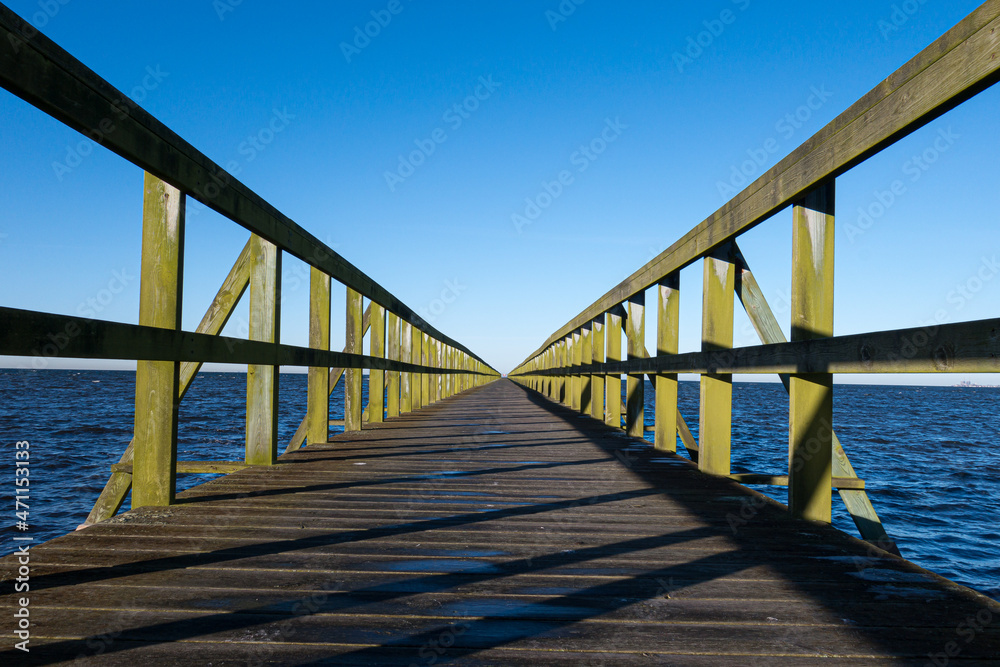 Timber pier leading away to clear blue sky horizon
