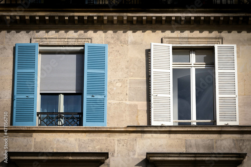 Old building in Paris with two windows, one white and one blue