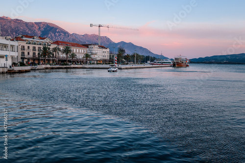 Yachts and boats on the embankment (pier) of the city of Tivat, Montenegro, the Balkans, the Bay of Kotor, the Adriatic Sea. Houses, mountains and sunset.