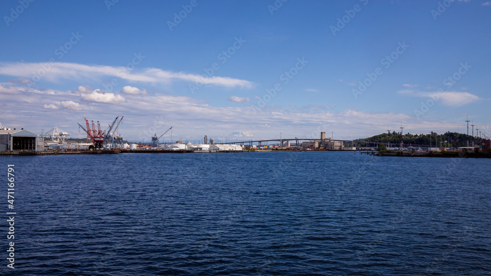 Seattle, Washington, USA - June 4 2021: Mount Rainier and Seattle Logistics shipping terminals waterway. View from Elliott Bay during summer.