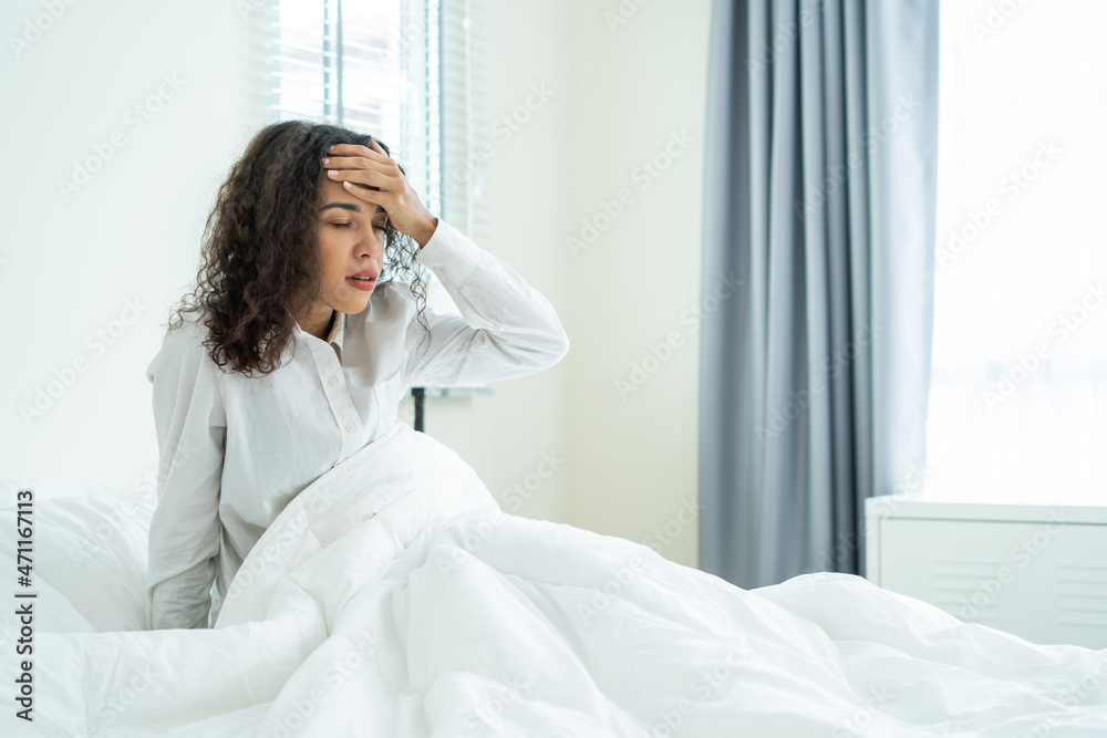 Latino beautiful girl in pajamas feel sick while sit on bed in bedroom. Latino beautiful girl in pajamas feel sick while sit on bed in bedroom.