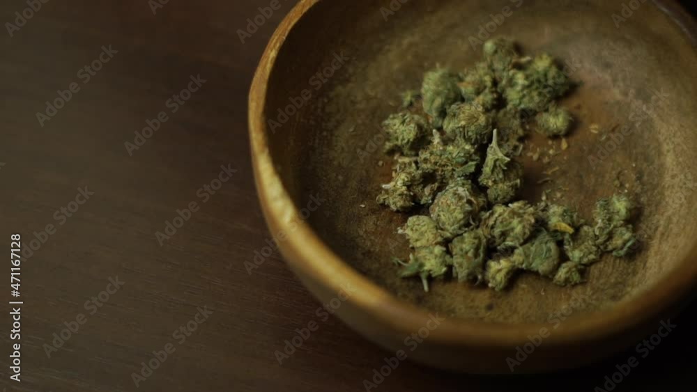 Top view cannabis buds in a wooden plate, female hand taking weed buds to smoke a joint. Decriminalization of marijuana. Legalization of medical cannabis Top view cannabis buds in a wooden plate, female hand taking weed buds to smoke a joint. Decriminalization of marijuana. Legalization of medical cannabis