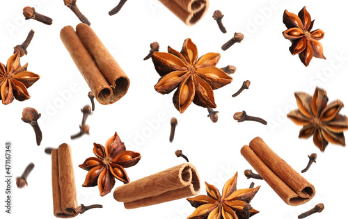 Aromatic anise stars, cinnamon and cloves falling on white background photo