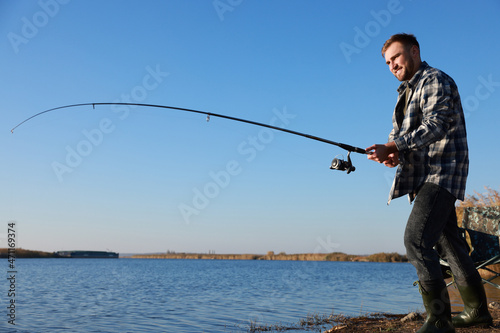 Fisherman with rod fishing at riverside. Recreational activity