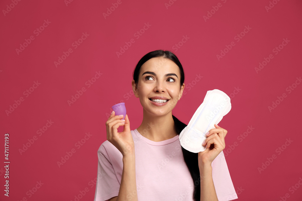 Young woman with menstrual cup and pad on bright pink background Young woman with menstrual cup and pad on bright pink background