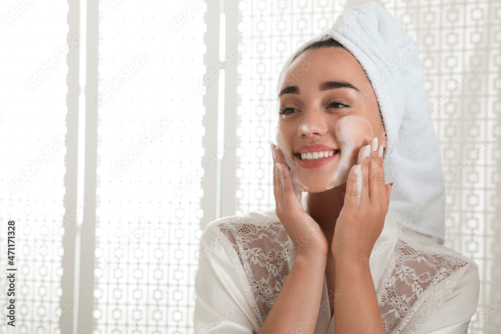 Beautiful young woman applying cleansing foam onto face in bathroom. Skin care cosmetic Beautiful young woman applying cleansing foam onto face in bathroom. Skin care cosmetic