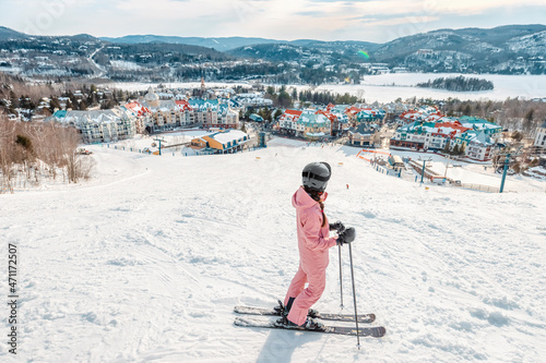 Skiing woman. Alpine ski - skier looking mountain village ski resort view starting skiing downhill on snow covered ski trail slope in winter. Mont Tremblant, Quebec, Canada