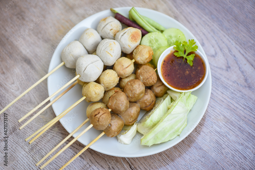 Meatballs on skewers on white plate and fresh vegetables cabbage yard long bean cucumber, Asian Thai food grilled meatballs fishball and porkball with picy sauce Meatballs on skewers on white plate and fresh vegetables cabbage yard long bean cucumber, Asian Thai food grilled meatballs fishball and porkball with picy sauce