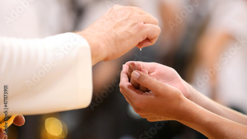 Close up image of a parishoners hands clasped receiving the bread during holy communion from a catholic priest at Mass.