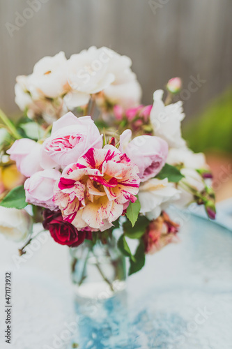 Fototapeta Naklejka Na Ścianę i Meble -  bunch of rose flowers in vase on top of outdoor table in sunny backyard