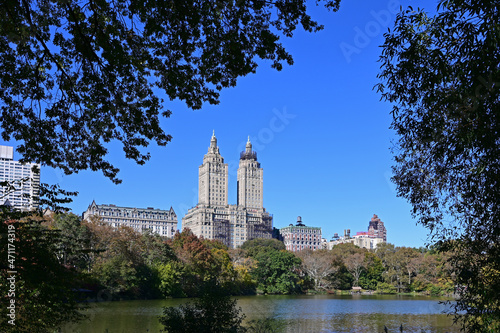 Central Park in New York with autumn foliage and skyscrapers in background on clear cloudless day.