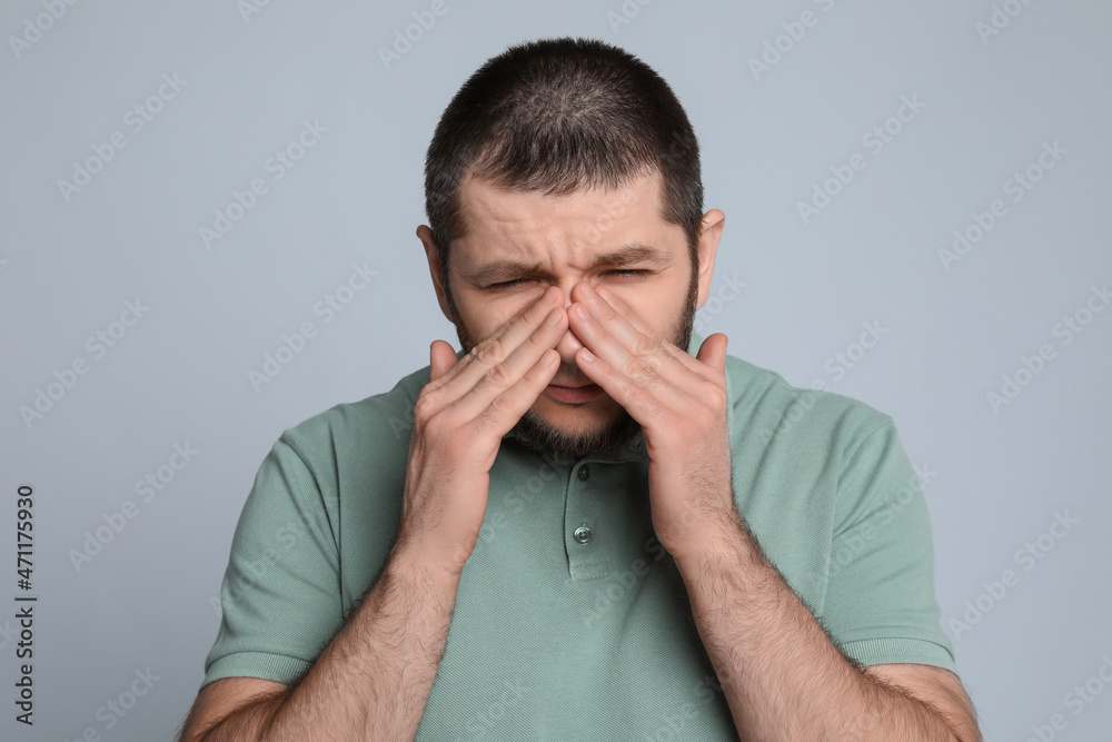 Man suffering from headache on light grey background Man suffering from headache on light grey background