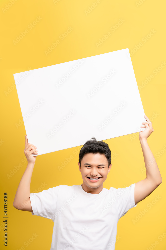 Excited young Asian man holding speech bubble with empty space for text studio shot isolated on the bright yellow wall Excited young Asian man holding speech bubble with empty space for text studio shot isolated on the bright yellow wall