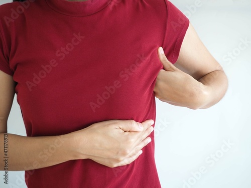 Young woman examining her breast for lumps or signs of breast cancer on white background. closeup photo, blurred.