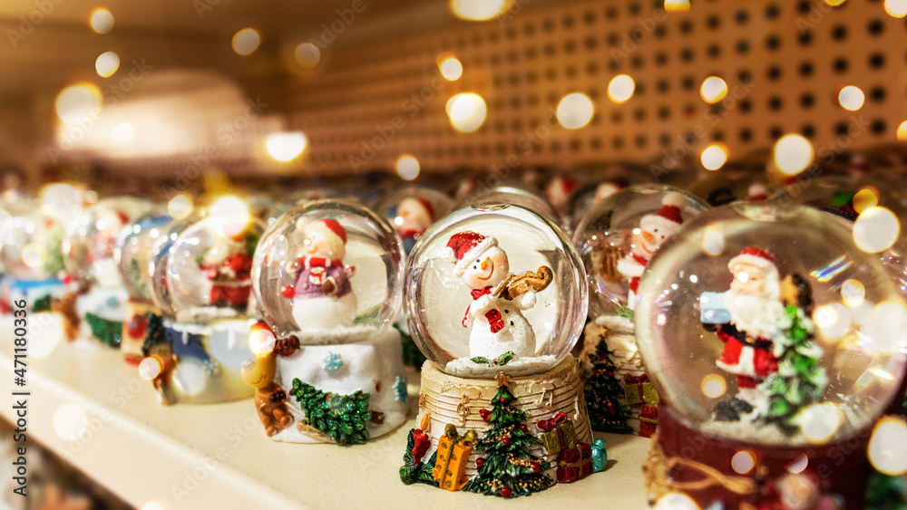 A Christmas glass ball with a snowman stands among other glass balls on a store shelf. Selective focus. Defocus lights.
Traditional symbolic small gift for Christmas. Christmas ball. Good New Year spi