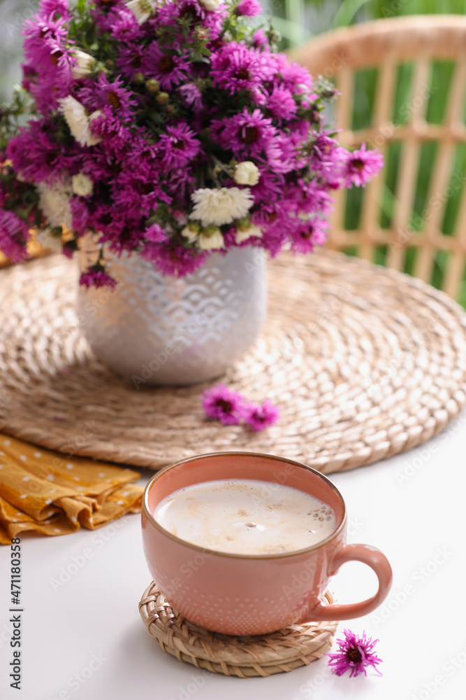 Cup of aromatic coffee and beautiful flowers on white table Cup of aromatic coffee and beautiful flowers on white table