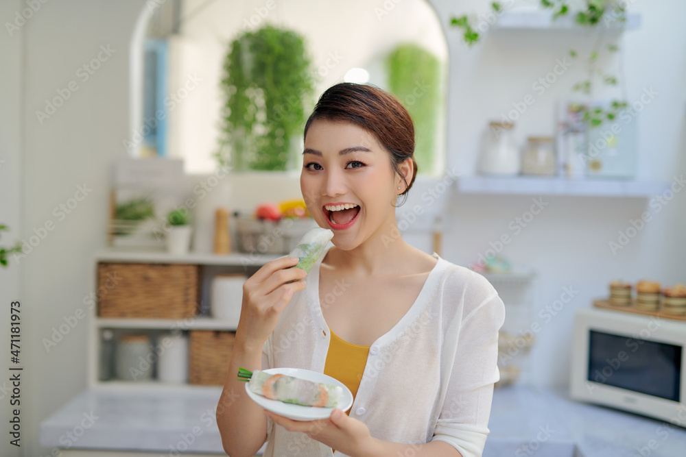 Asian woman eating tasty traditional spring rolls Asian woman eating tasty traditional spring rolls