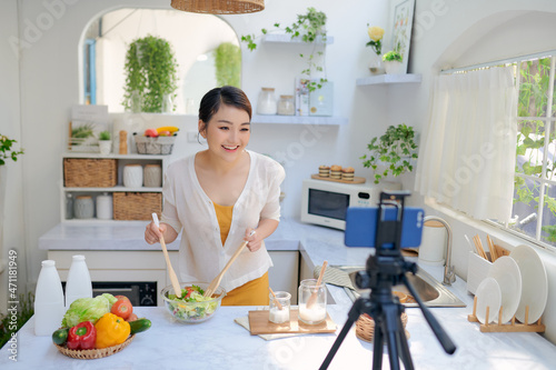 Asian beautiful woman recording her cooking video using a mobile phone.