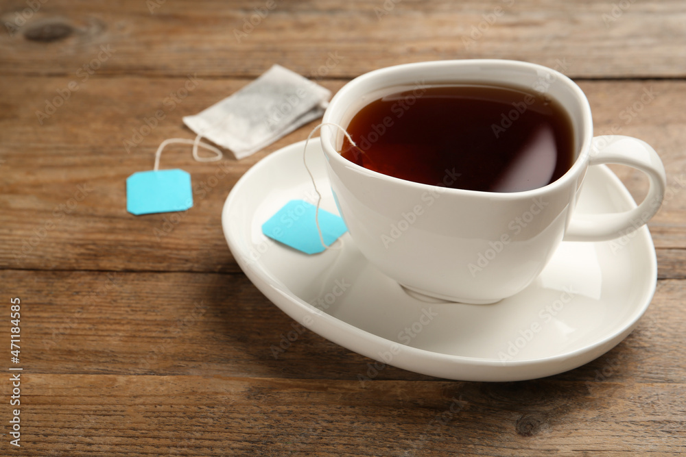 Tea bag in ceramic cup of hot water on wooden table. Space for text