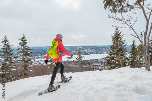 Fototapeta Snowshoeing people in winter forest with snow covered trees on snowy day