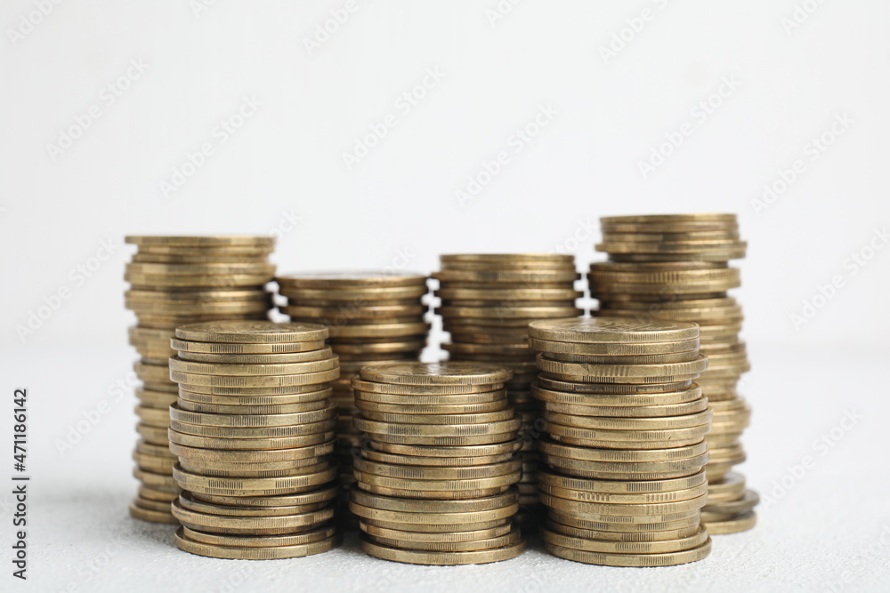 Many golden coins stacked on white table Many golden coins stacked on white table