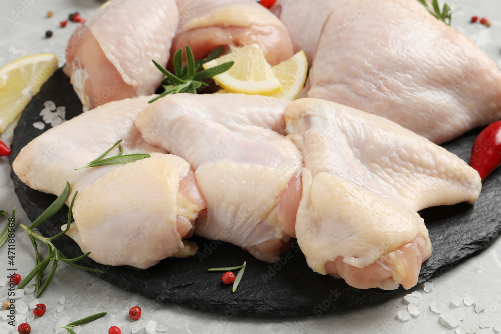 Fresh raw chicken meat and other products on slate board, closeup Fresh raw chicken meat and other products on slate board, closeup