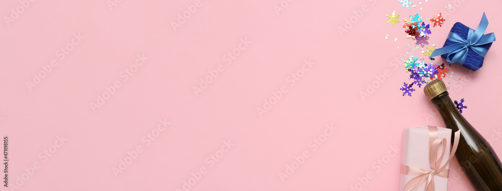 Bottle of champagne with Christmas gifts and confetti on pink background with space for text Bottle of champagne with Christmas gifts and confetti on pink background with space for text