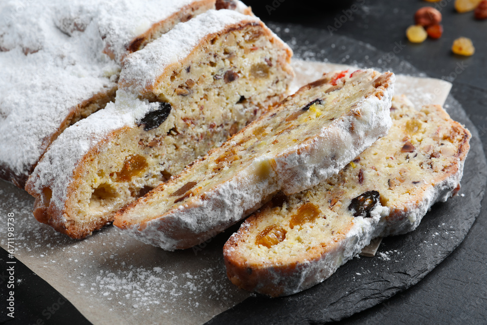Traditional Christmas Stollen with icing sugar on black table, closeup Traditional Christmas Stollen with icing sugar on black table, closeup