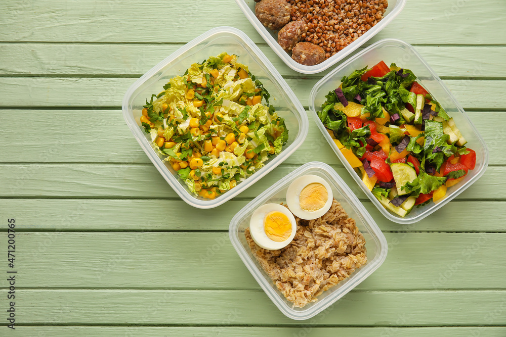 Containers with tasty healthy food on color wooden background