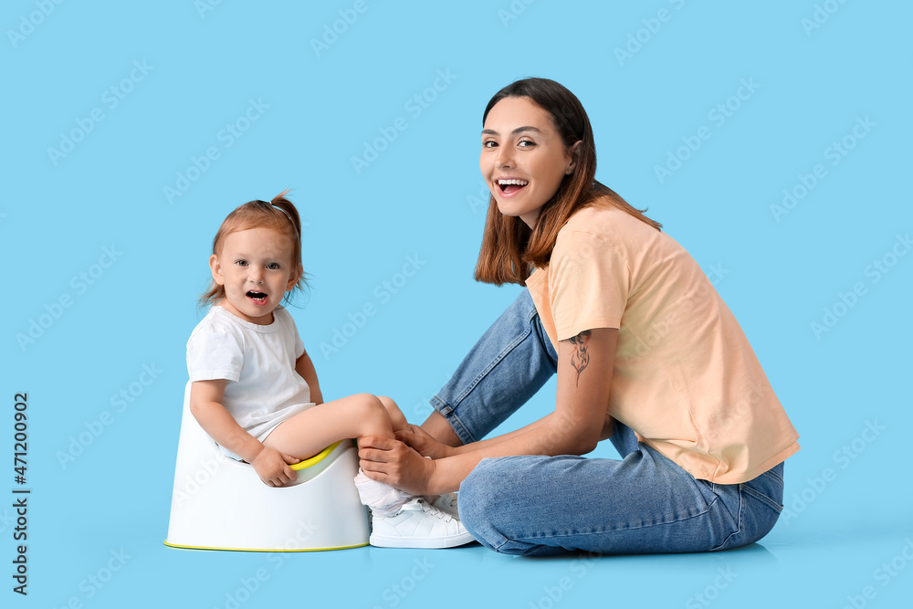Mother potty training her little daughter on color background Mother potty training her little daughter on color background