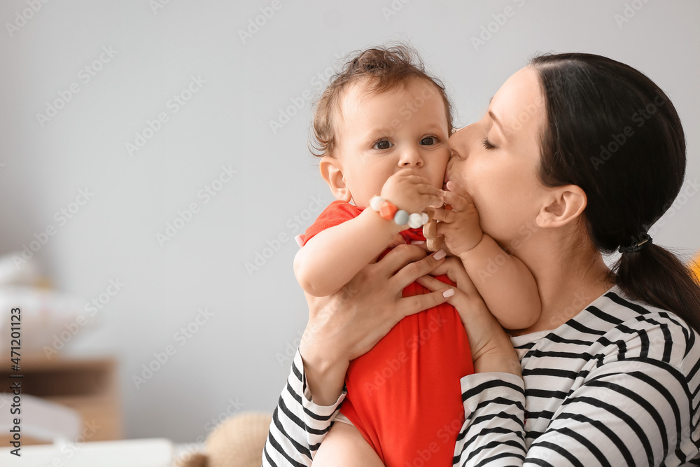 Young mother kissing her little baby with toy in bedroom Young mother kissing her little baby with toy in bedroom